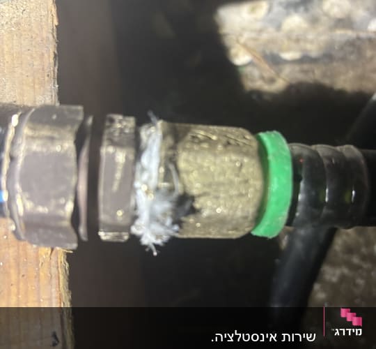 חיבור צינור עם אטם ירוק ועץ ברקע